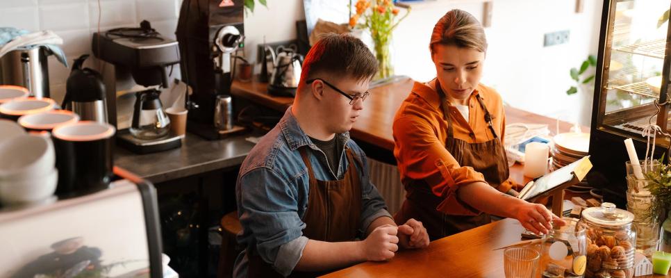 Two workers at the counter of a coffee shop.